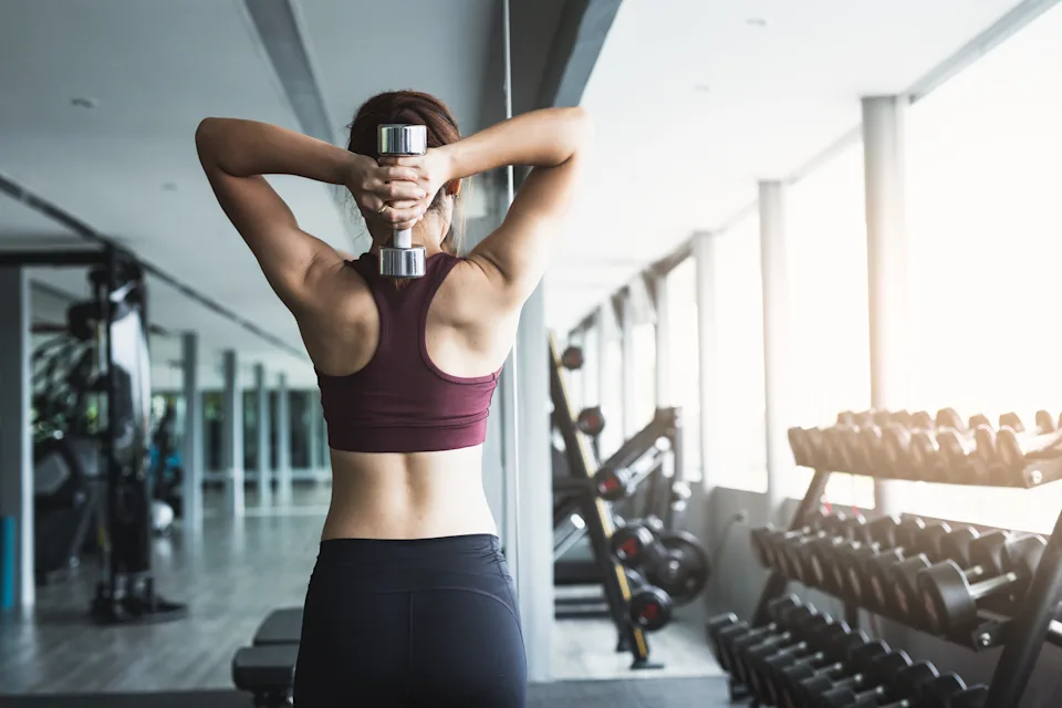 Fitness woman lifting dumbbell at gym.